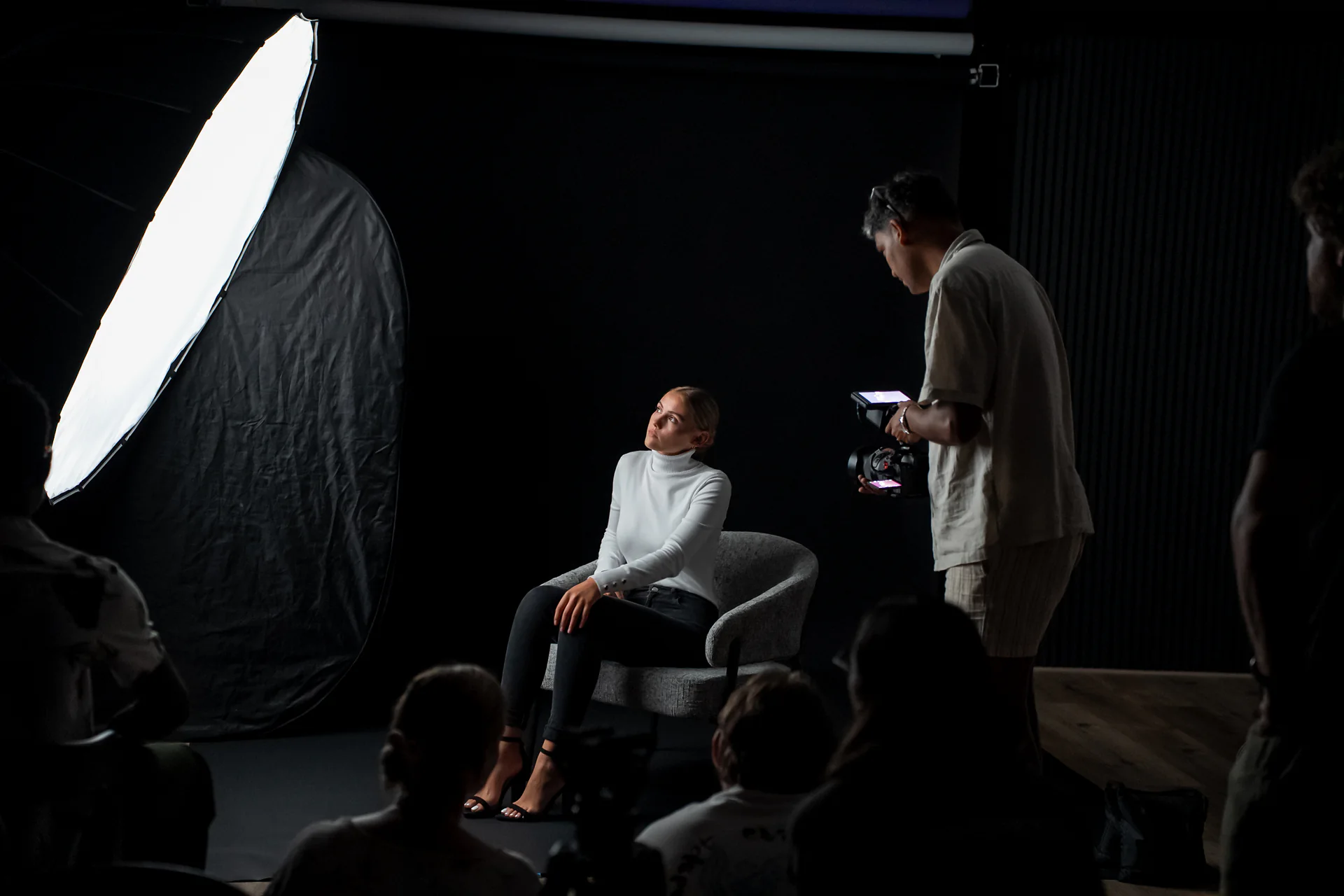 A seated subject being lit during a practical demonstration inside Studio GQ